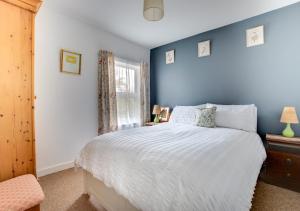 a blue bedroom with a bed and a window at Clyde Cottage in Saxmundham