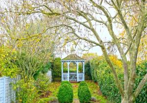 a gazebo in a garden with trees and bushes at Christmas Cottage in Southwold