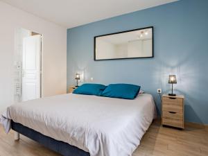 a bedroom with a large bed with blue walls at Holiday Home La peite maison by Interhome in Gouville-sur-Mer
