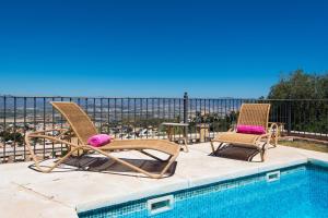 duas cadeiras e uma mesa ao lado de uma piscina em VILLA ANDALUCIA ATLANTIDA, casa con piscina privada em Alhaurín de la Torre