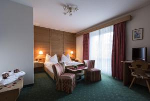 ein Hotelzimmer mit einem Bett, einem Tisch und Stühlen in der Unterkunft Hotel Cosmea in St. Ulrich in Gröden