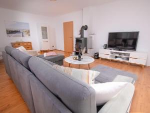 a living room with a gray couch and a tv at Holiday Home Kiek in by Interhome in Norden
