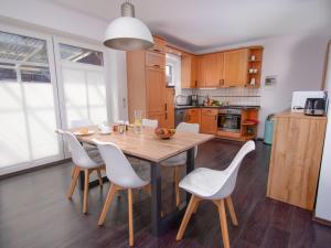 a kitchen with a wooden table and white chairs at Holiday Home Kiek in by Interhome in Norden