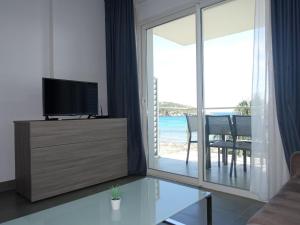 uma sala de estar com uma televisão e uma porta de vidro deslizante em Apartment Villa Tyrrenia-3 by Interhome em Rogliano