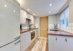 a kitchen with white cabinets and wooden floors at Cockleshell Cottage in Kessingland