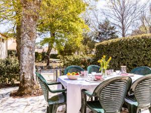 a table with a white tablecloth and green chairs at Holiday Home Les Maisons de l'Océan-1 by Interhome in Les Mathes