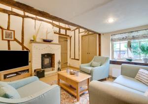 a living room with a tv and a fireplace at Cobblers Cottage in Bramfield