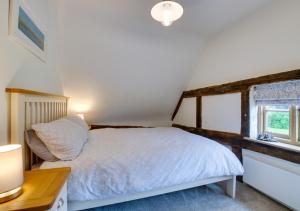 1 dormitorio con cama, escritorio y ventana en Cobblers Cottage en Bramfield