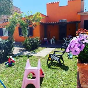 pomarańczowy dom z ogródkiem z zabawkami w trawie w obiekcie Casa Mare al Circeo w mieście San Felice Circeo