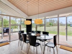 comedor con mesa, sillas y ventanas en Holiday Home Segelferd - 650m from the sea in NW Jutland by Interhome, en Løkken