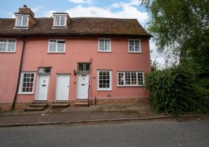 a pink house with white doors on a street at Coppers in Lavenham