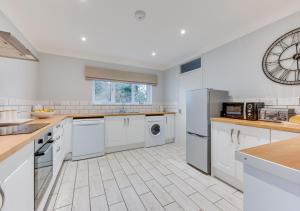 a kitchen with white appliances and a clock on the wall at Dakings in Halesworth