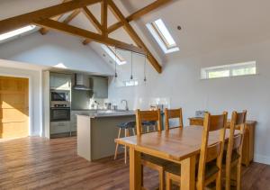 a kitchen and dining room with a wooden table and chairs at Daisy Lodge in Blyford