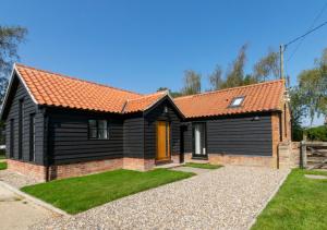 a black house with an orange roof at Daisy Lodge in Blyford