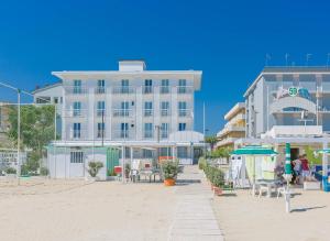a white building on the beach with tables and chairs at Hb Hotels Orchidea Blu in Rimini