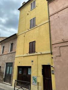 ein gelbes Gebäude mit zwei Fenstern und zwei Türen in der Unterkunft L'inchiostro di Dante in Macerata