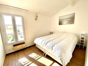 Un dormitorio con una gran cama blanca y dos ventanas. en AGATHE Bel appartement avec piscine, en La Flotte