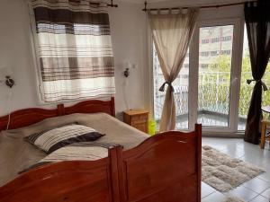 um quarto com uma grande cama de madeira e uma janela em Апартамент за гости Сънрайз с гледка към река Дунав em Ruse