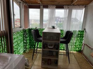 uma cozinha com 2 cadeiras, uma mesa e janelas em Апартамент за гости Сънрайз с гледка към река Дунав em Ruse