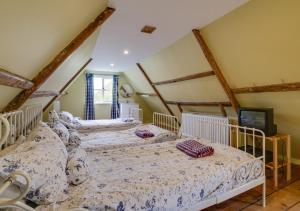 três camas num quarto com vigas de madeira em Dressmakers Cottage em Wrentham