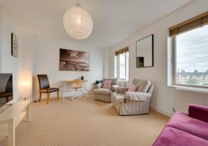 una sala de estar con un sofá púrpura y sillas en Dunlin en Southwold