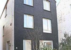 un edificio de ladrillo negro con ventanas blancas. en Dunlin en Southwold