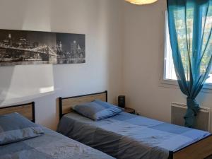 1 dormitorio con 2 camas y ventana en Le Circuit du Soleil, en Lédenon