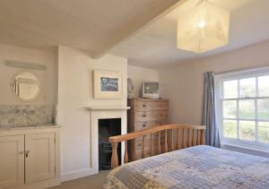 a bedroom with a bed and a fireplace and a window at Easter Cottage in Westleton