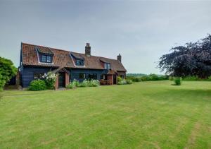 a house with a large grass field in front of it at Eelsfoot Cottage in Hemley