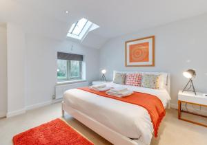 a white bedroom with a large bed and a window at East Barn Cottage in Aldringham