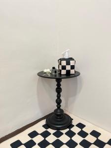 a black table with a cake on it on a checkered floor at The Neighbour KKB - Rooms with shared bathroom in Kuala Kubu Baharu