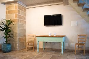 a table with chairs and a tv on a wall at Nonna Elvira in Specchia Gallone