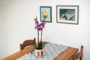 a dining room table with a vase with purple flowers at Apartments Karolina in Novalja