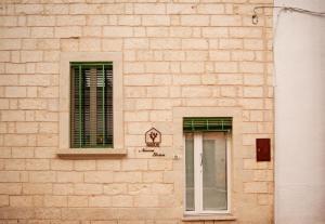 - un bâtiment en briques avec deux fenêtres et une porte dans l'établissement Nonna Elvira, à Specchia Gallone