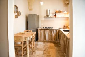 a kitchen with a wooden table and a refrigerator at Nonna Elvira in Specchia Gallone