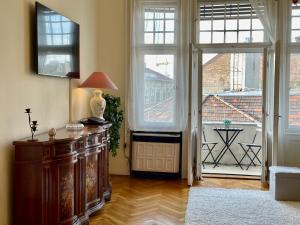 sala de estar con ventanas grandes y mesa con lámpara. en Jolan Suite, en Budapest