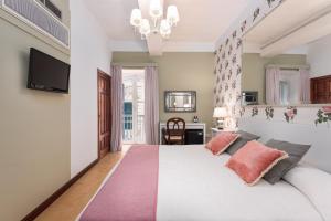 a bedroom with a large white bed with pink pillows at Hotel Castille in Valletta