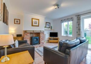 uma sala de estar com dois sofás de couro e uma lareira em Field End em Reydon