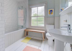 uma casa de banho com um lavatório, um WC e uma janela. em Fern Cottage em Walberswick