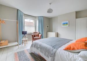 a bedroom with a bed and a chair and a window at Fern Cottage in Walberswick