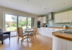 a kitchen with a table and chairs and a large window at Gleve House in Marlesford