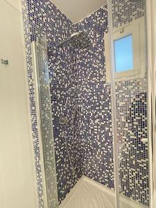 um chuveiro de azulejos azuis e brancos com uma porta de vidro em Casa dei Visionari 2 em Bari