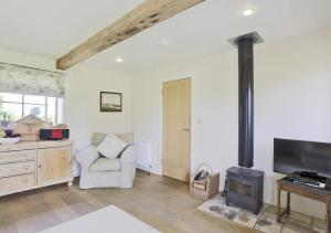 a living room with a wood stove and a chair at Harrow Cottage in Yoxford