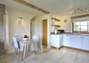 cocina con mesa con sillas y fregadero en Harrow Cottage, en Yoxford