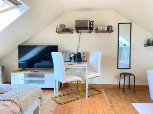 um quarto com uma secretária, uma televisão e 2 cadeiras em Mini-studio by HNFC Stays em South Shields