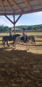 dos personas montando a caballo en una arena en Boldizsár Lovas Ház, en Cserépfalu