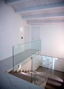 a glass staircase in a white room with wooden ceilings at LAURIA Luxury Room in Gela