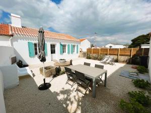 un patio con sombrilla, mesa y sillas en La Maison de Lena 500m de la Plage en Barbâtre