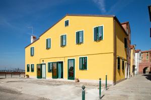 un edificio amarillo con puertas verdes en una calle en Dimora Stella en Pellestrina