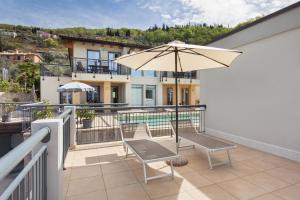 patio con sombrilla y sillas en el balcón en Casa Al Lago With Pool, en Torri del Benaco